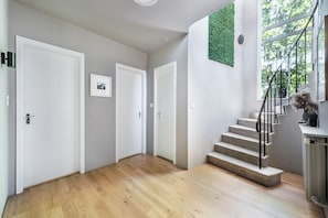 Ein modernes Interieur mit Holzboden, weißen Wänden, einer Treppe und einer Wand in Grünton.