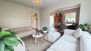 A modern living room with a beige sofa, a coffee table, and a dining area with a table and chairs. - Modern and family friendly house in Reykjavik (Reykjavík)