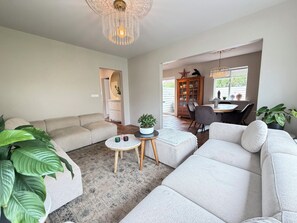 Ein modernes Wohnzimmer mit einem beigen Sofa, einem Couchtisch und einem Essbereich mit Tisch und Stühlen.