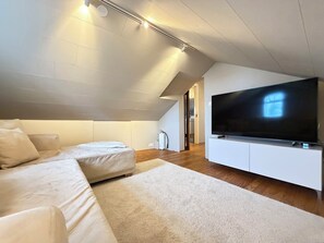 Ein modernes Wohnzimmer mit einem großen Flachbildfernseher, einer Couch und einem Teppichboden.