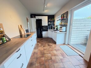 A modern kitchen with white cabinets, a black refrigerator, and a built-in oven. - Modern and family friendly house in Reykjavik (Reykjavík)