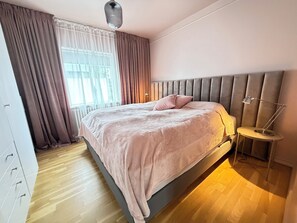 A modern bedroom with a bed, a bedside lamp, and a window with curtains. - Modern and family friendly house in Reykjavik (Reykjavík)
