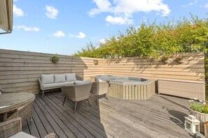 A wooden deck with wicker furniture, a hot tub, and a wooden wall with planters. - Modern and family friendly house in Reykjavik (Reykjavík)