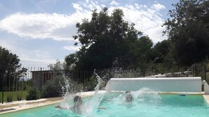A swimming pool with clear water, surrounded by trees and a fence.