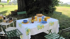 An outdoor dining setup with a table set for two, surrounded by greenery.