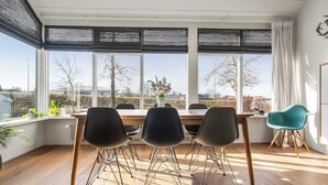 Ett modernt matområde med ett träbord, tre stolar och utsikt genom stora fönster.