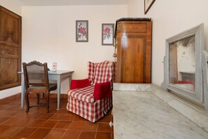 A room with a wooden cabinet, a chair, a table, and a fireplace.