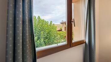 Una ventana con vista a un paisaje verde y un edificio de techo rojo.