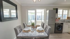 Un comedor con una mesa de mármol, sillas tapizadas y un espejo grande en la pared.