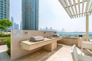 Eine Dachterrasse mit Grill, Sitzgelegenheiten und Blick auf die Stadtlandschaft.