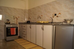 Una cocina con estufa, horno, refrigerador y salpicadero de azulejos.