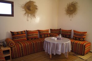 Une pièce comprenant un ensemble de canapés, une table ronde et deux chapeaux de soleil fixés au mur.