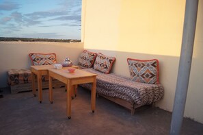 Un pequeño balcón con sofá y mesa, vista al paisaje y un cojín estampado.