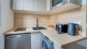 Una cucina funzionale con lavastoviglie, lavatrice, forno a microonde e macchina da caffè.
