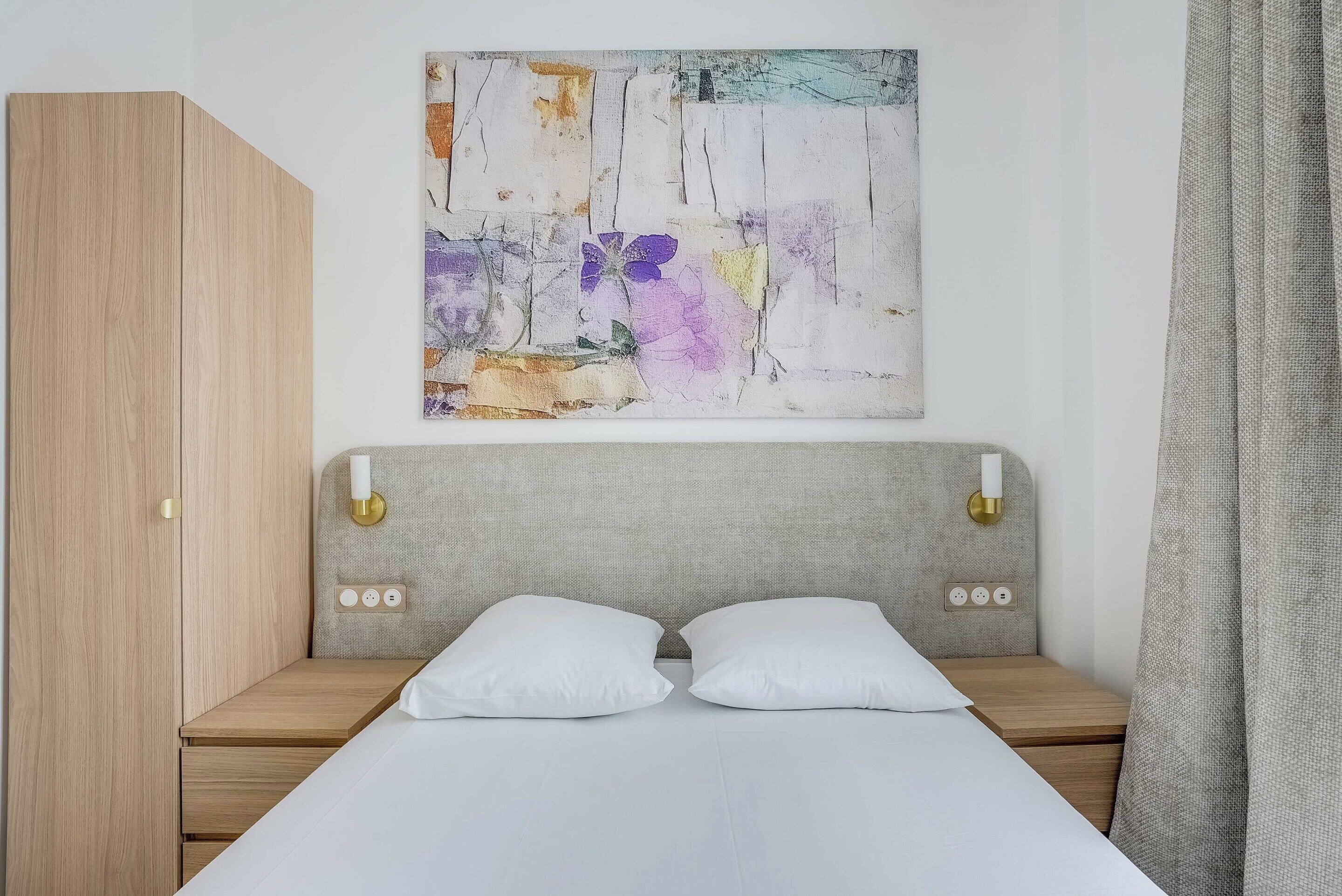 Een slaapkamer met een bed, twee nachtkastjes, een hoofdbord, een kledingkast en een abstract schilderij aan de muur.