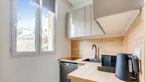 Una cucina compatta con lavastoviglie, macchina del caffè e una finestra vista edifici.