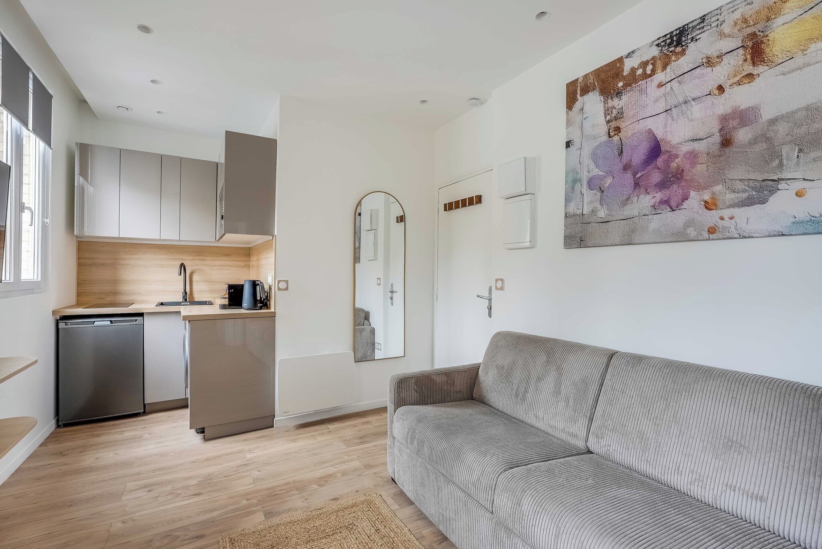 A modern kitchen with built-in appliances, a sofa, and a large abstract painting.