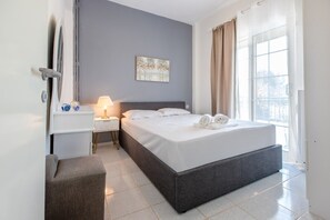 Ein Hotelzimmer mit Bett, Nachttisch, Lampe, einem Gemälde und Blick ins Freie.