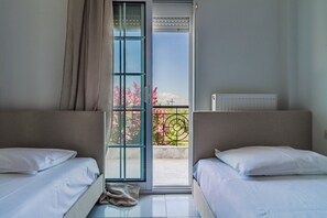 Un dormitorio con dos camas, un ventanal corredero que da a un balcón y un radiador en la pared.