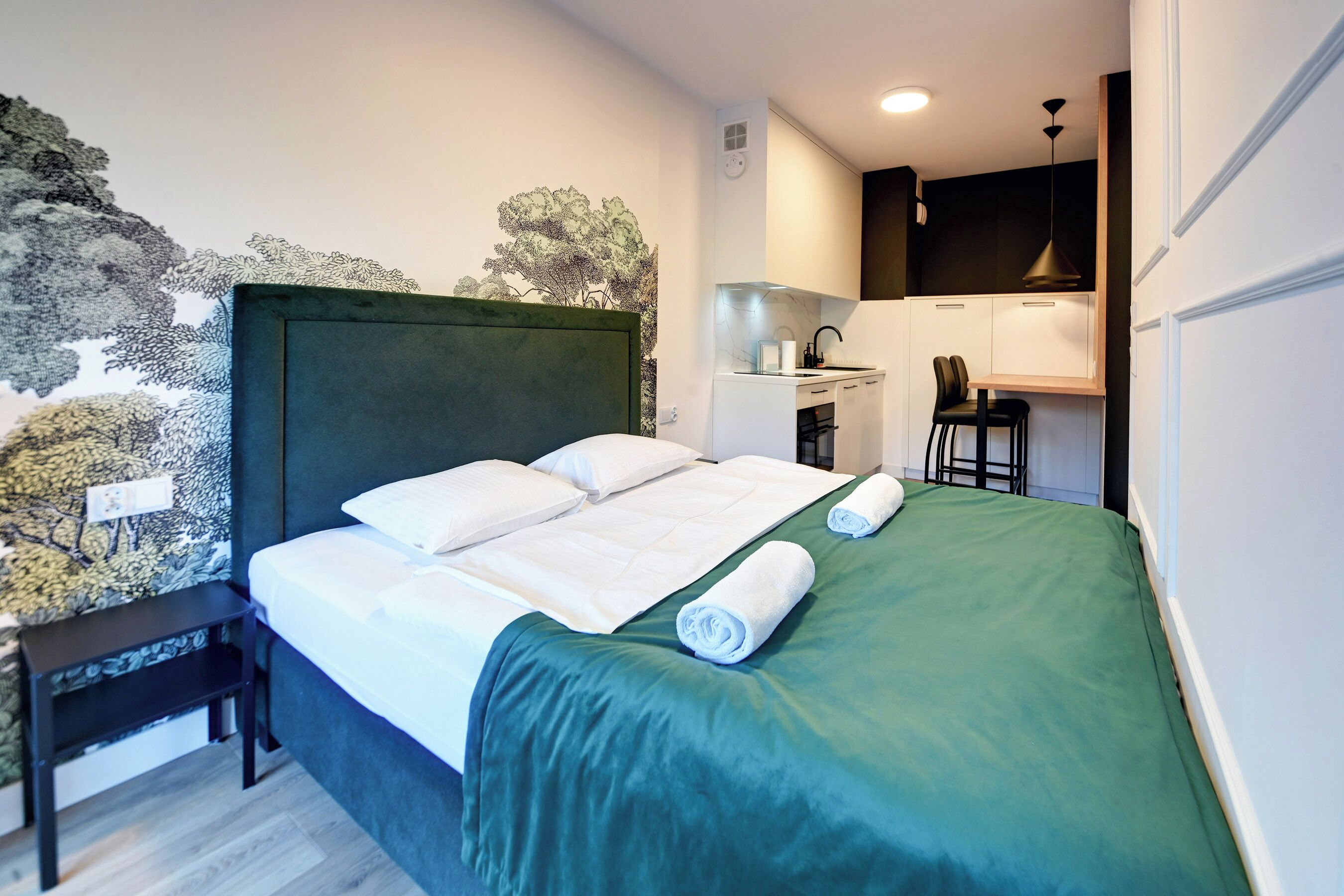 A hotel room with a bed, a desk, and a kitchenette.