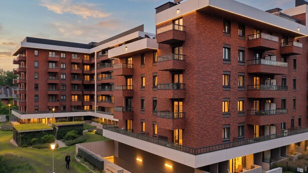 Un edificio de varios pisos con balcones, techo plano y una entrada bien iluminada.