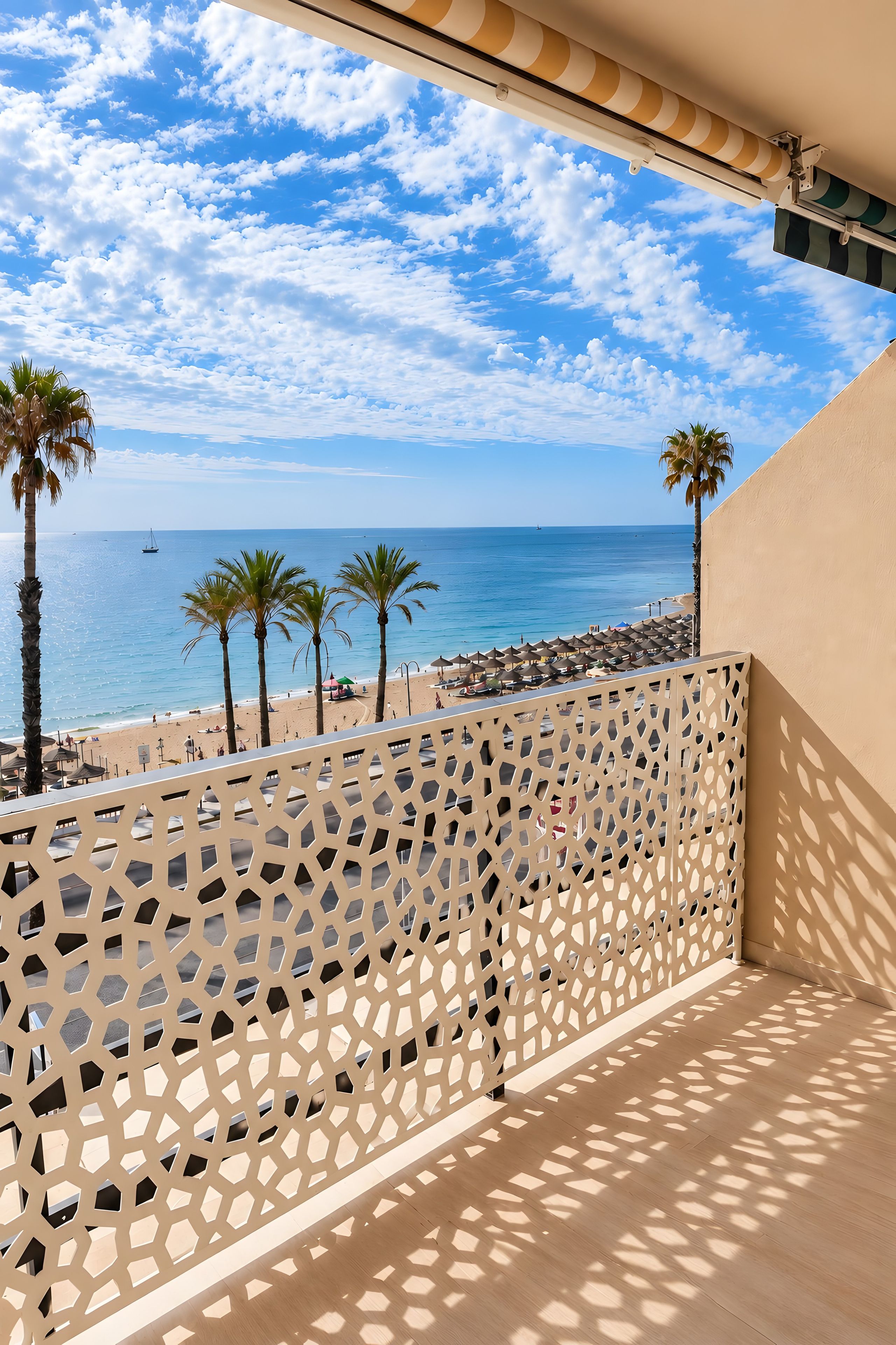 A balcony with a view of the beach, palm trees, and the sea.