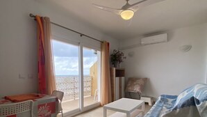 A room with a bed, a table, a chair, a ceiling fan, and a view through a glass door. - Terrace with Sea Views at Castillo Bil Bil, Benalmádena (Benalmádena)