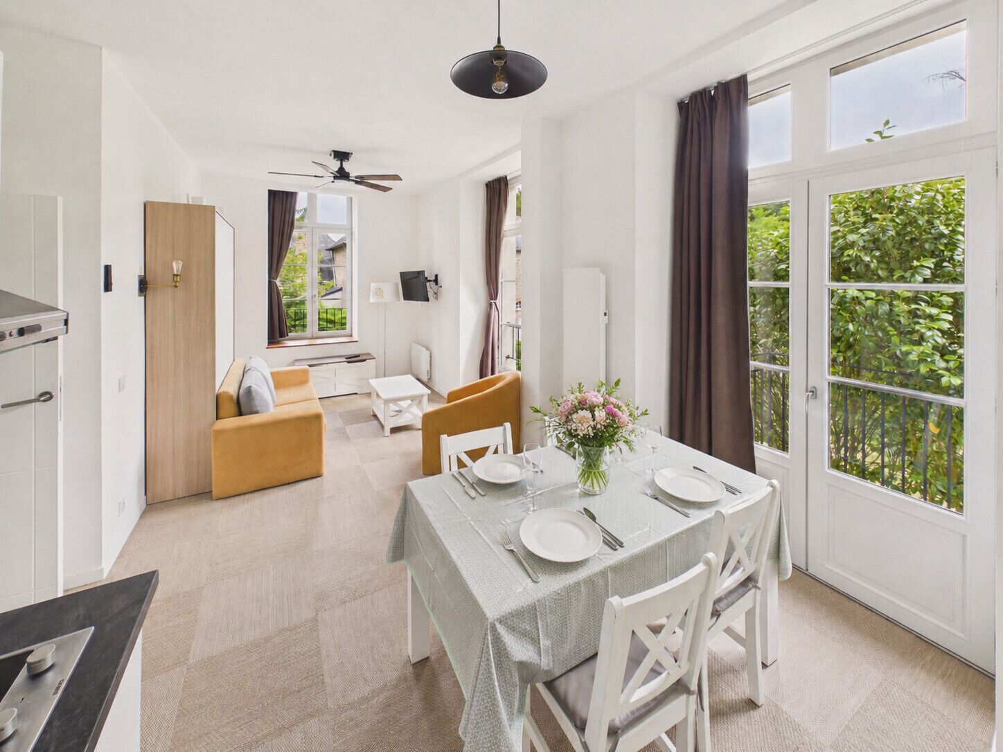 A modern kitchen with a dining area, a sofa, and a table set for two.