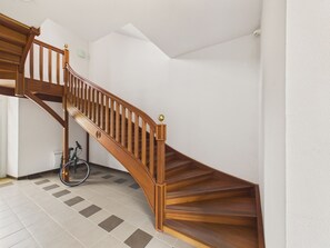 Eine Holztreppe mit Handlauf, einem Fahrrad und einem Fliesenboden.