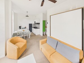 A modern living room with a sofa, a dining table, and a kitchen area in the background. - Apartment in a castle with pool – 4 guests (Baden)
