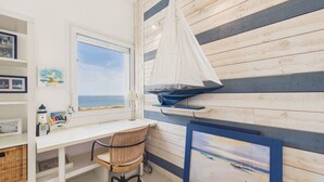 Ett rum med ett skrivbord, en stol och ett stort fönster med utsikt över havet.