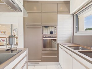 A modern kitchen with built-in appliances, a window, and a view of the outdoors. - 150m from the beach, 6-guest home with terrace (Piriac-sur-Mer)