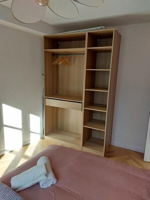 A bedroom with a bed, a wooden wardrobe, and a window.