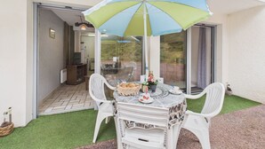 A patio with a table, chairs, and a table umbrella. - 700 m from beach , flat for 4 with terrace (Jard-sur-Mer)