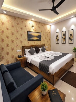 Ein modernes Hotelzimmer mit Bett, Sofa, Nachttisch und Deckenventilator.