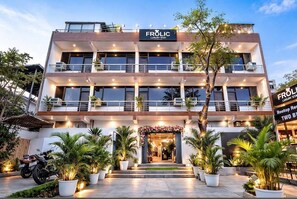 A multi-story building with balconies, a sign reading 'FROLIC LUXURY STAY,' and potted plants in front. - Hotel SV Near Noida Metro Station 52 (Noida)