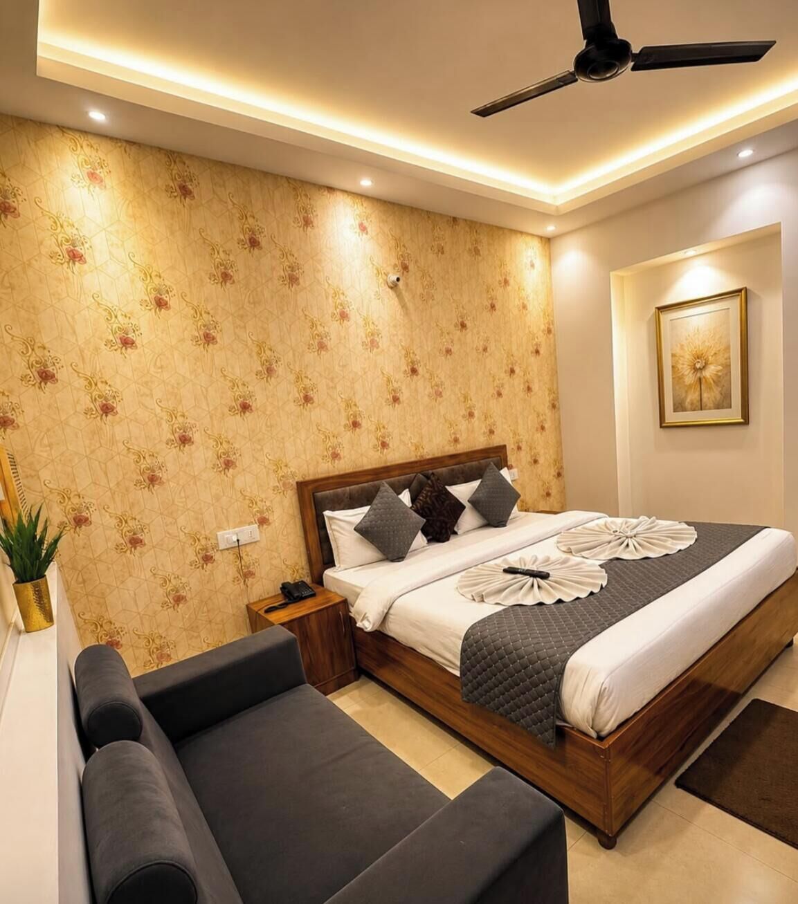 A bedroom with a bed, bedside table, nightstand, and a ceiling fan.