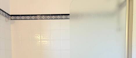 A bathroom with a bathtub, toilet, and a shower enclosure.