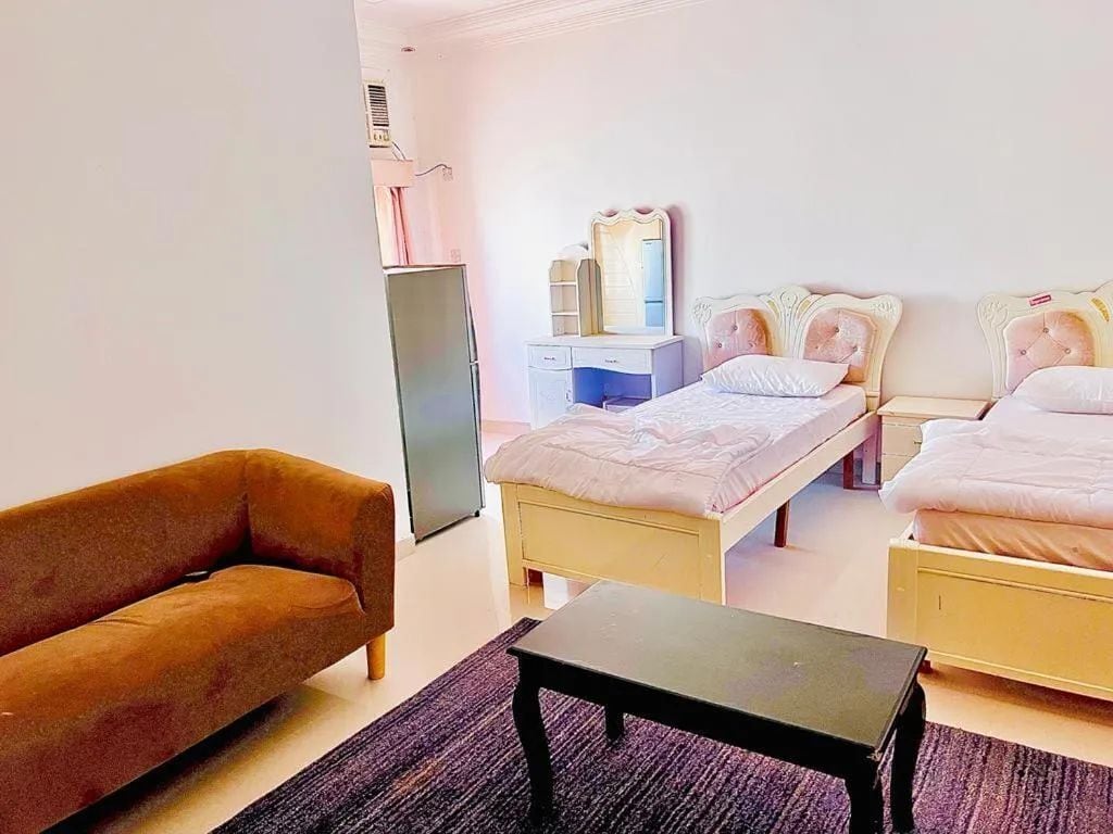 Une chambre avec deux lits, un canapé, une table de chevet, une commode et un miroir.
