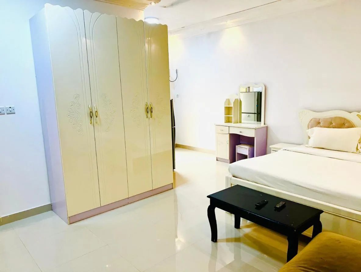 Une chambre à coucher avec un lit, une table de chevet, une armoire et un miroir.