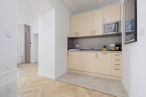 Eine moderne Küche mit hellen Holzschränken, einer Edelstahl-Mikrowelle und einer kleinen Arbeitsfläche.