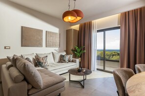 A modern living room with a sofa, coffee table, and a view of the outdoors. - Ark Luxury Suite with Hot tub and Sea Views (Zakynthos)