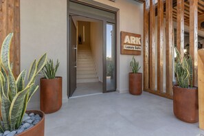 A building entrance with a staircase leading inside, a sign reading 'ARK Luxury Suite,' and potted plants. - Ark Luxury Suite with Hot tub and Sea Views (Zakynthos)