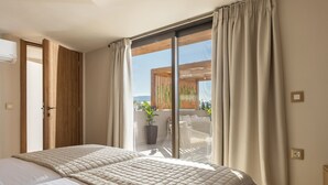 Un dormitorio con una cama grande, una puerta corrediza al balcón y vistas al exterior.