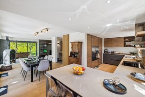 Eine moderne Küche mit Holzausstattung, einer zentralen Kochinsel und einem Essbereich mit Tisch und Stühlen.