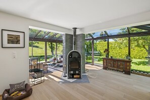 Un salon moderne avec une cheminée, un patio fermé par des baies vitrées et une vue sur un jardin.