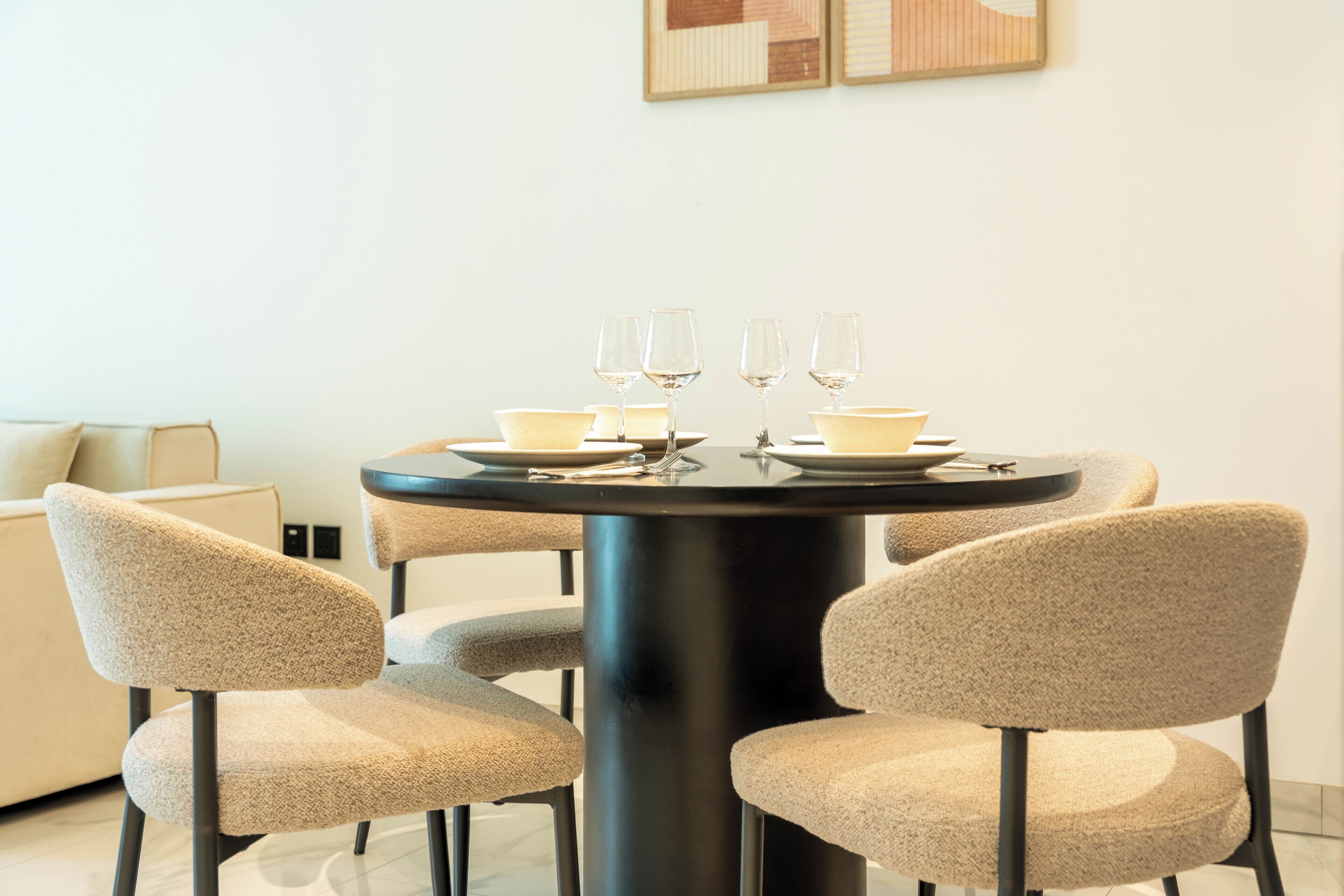 A dining area with a round table, four chairs, and four wine glasses.