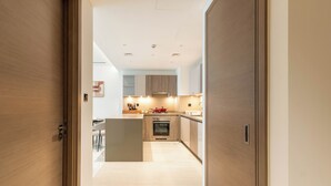 A modern kitchen with wooden cabinets, a central island, and built-in appliances. - Skyline Views - 39th Floor Apartment (Dubai)