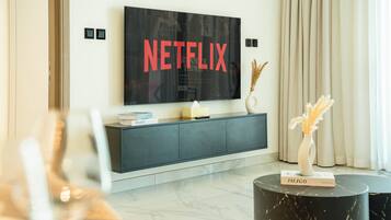 Leilighet – deluxe, balkong, bassengutsikt | Oppholdsområde | En 57-tommers Flatskjerm-TV med Parabol-TV