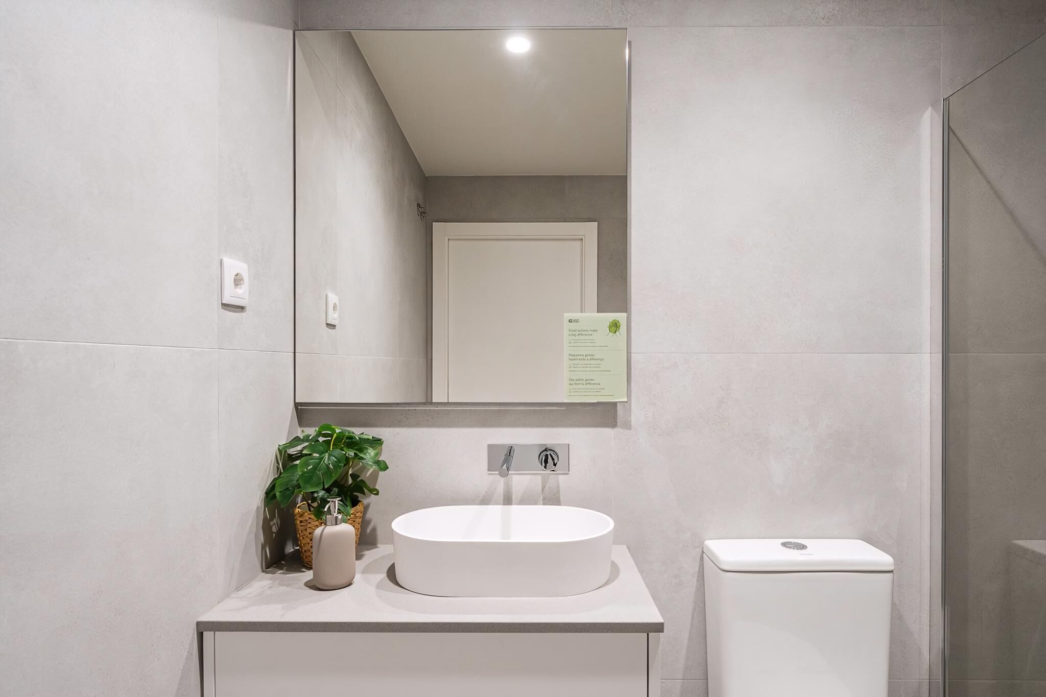 Un baño moderno con un lavamanos blanco, un espejo y un inodoro.